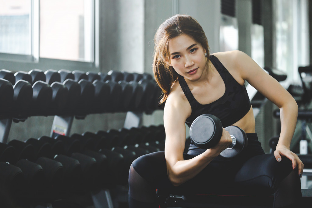 woman in gym clothes lifting dumbbells